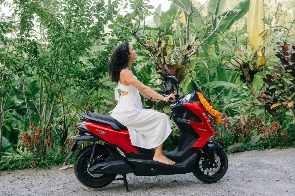 Rider seated on a red electric motorbike on a garden lane