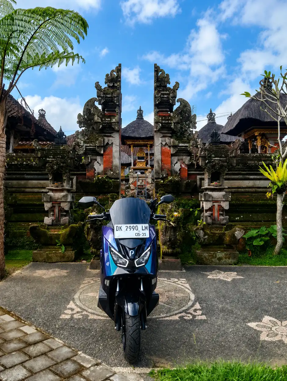 Electric motorbike parked in front of a Balinese temple gate